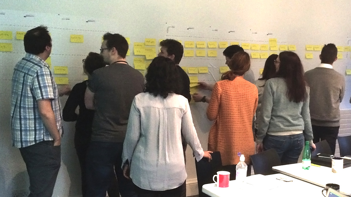 A group of people looking at a wall covered in sticky notes