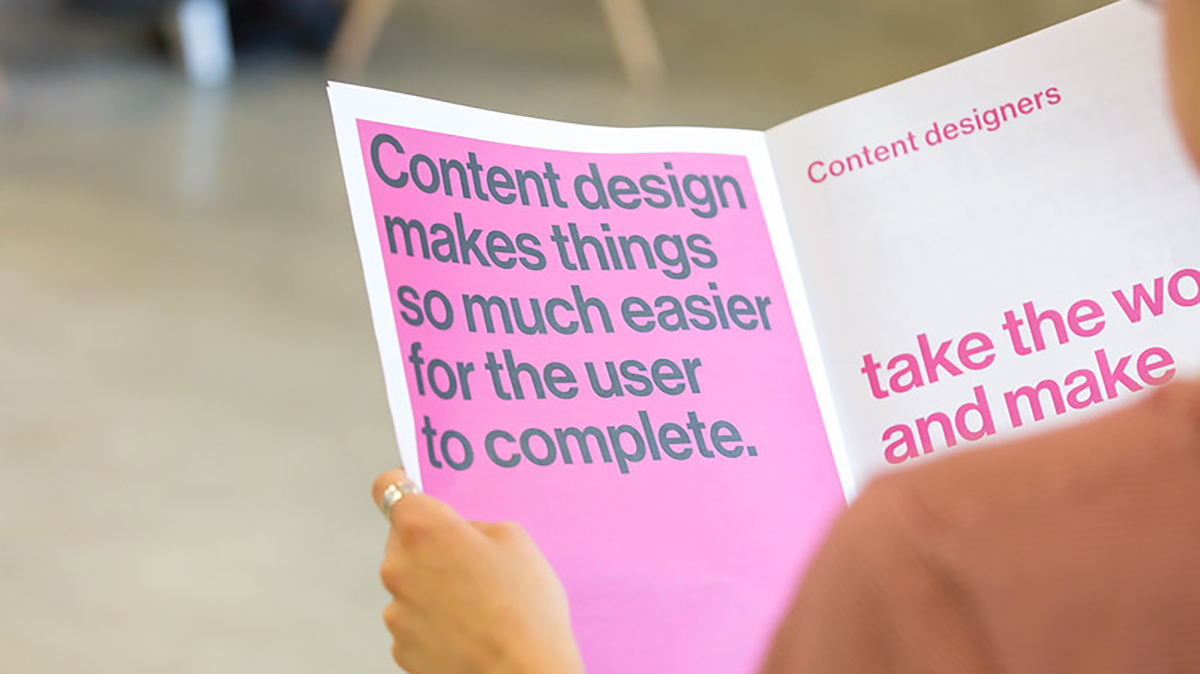 Someone reading a magazine about content design. On the page it says ‘Content design makes things so much easier for the user to complete’